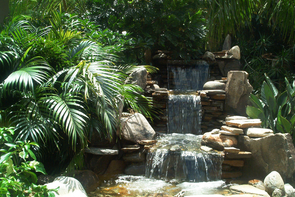 Idee per una grande piscina monocorsia etnica rettangolare dietro casa con fontane e pavimentazioni in pietra naturale