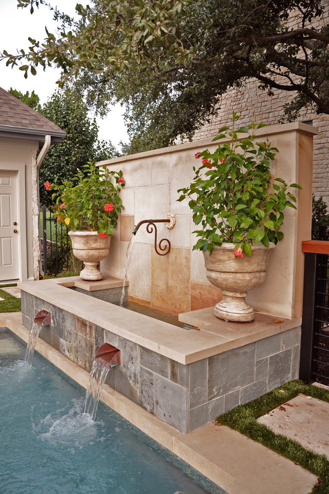 Inspiration for a large traditional back rectangular swimming pool in Austin with a water feature.