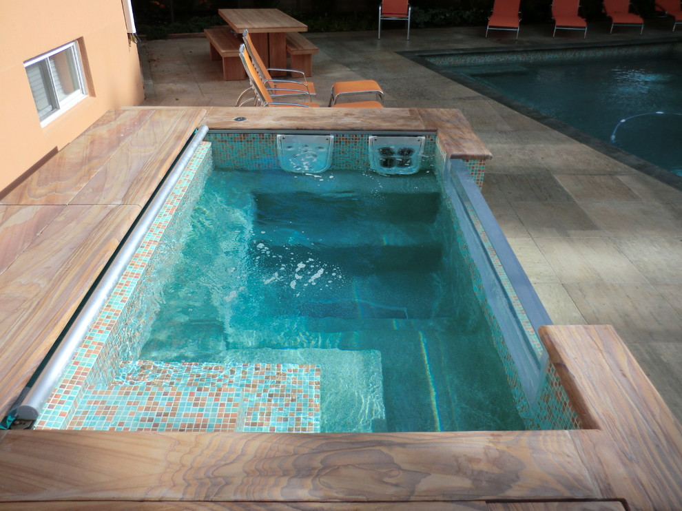 На фото: маленький наземный, прямоугольный бассейн на заднем дворе в стиле модернизм с джакузи и покрытием из каменной брусчатки для на участке и в саду с