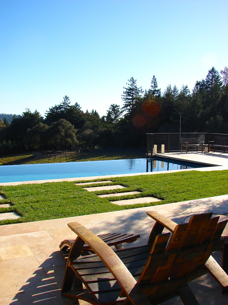 Imagen de piscina infinita minimalista grande rectangular en patio trasero con adoquines de piedra natural