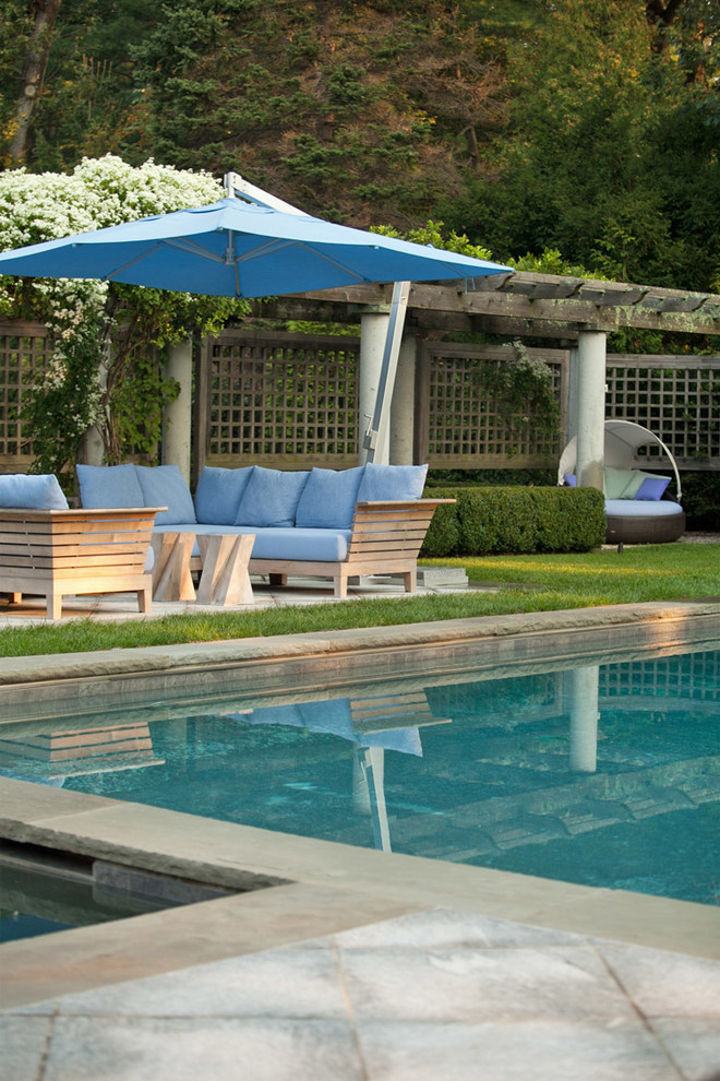 Diseño de piscina minimalista grande rectangular en patio trasero con adoquines de piedra natural
