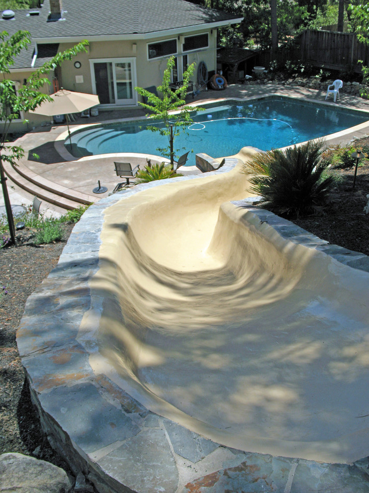 Photo of a medium sized rustic back custom shaped lengths swimming pool in San Francisco with a water slide and stamped concrete.