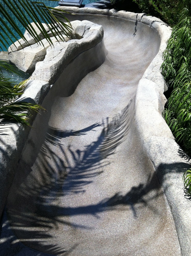 Foto de piscina con tobogán natural exótica de tamaño medio en patio trasero