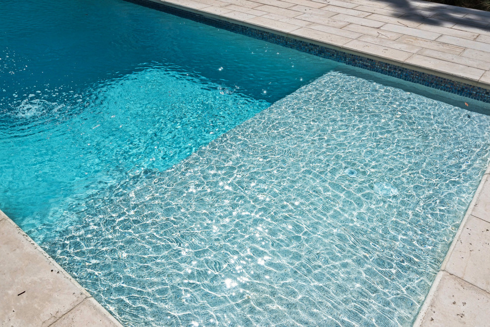 Ejemplo de piscina minimalista pequeña rectangular en patio trasero con adoquines de hormigón