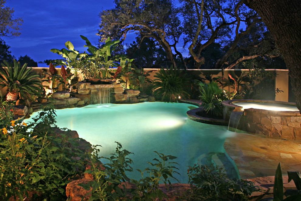 Esempio di una piscina naturale tropicale personalizzata di medie dimensioni e dietro casa con pavimentazioni in pietra naturale e una vasca idromassaggio