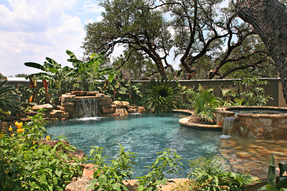 Example of a mid-sized island style backyard stone and custom-shaped natural hot tub design in Austin