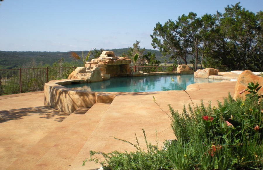 Diseño de piscina con fuente elevada tradicional de tamaño medio a medida en patio trasero con losas de hormigón