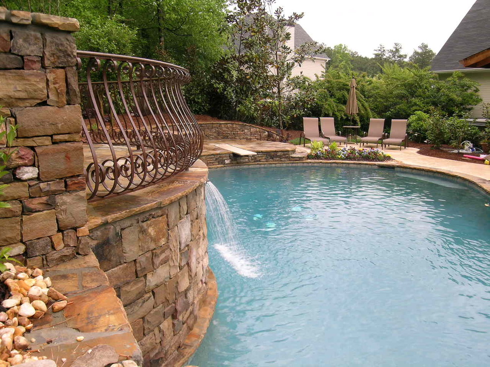 Imagen de piscina con fuente natural tradicional grande a medida en patio trasero con adoquines de piedra natural