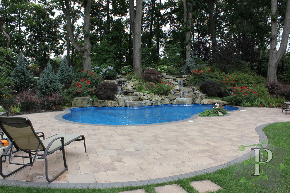 Imagen de piscina con fuente clásica de tamaño medio tipo riñón en patio trasero con adoquines de hormigón
