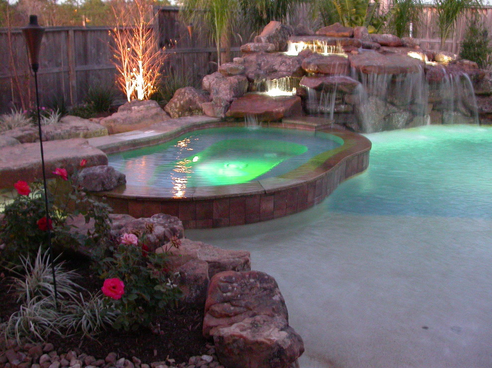 Inspiration for a large timeless backyard stamped concrete and custom-shaped hot tub remodel in Houston