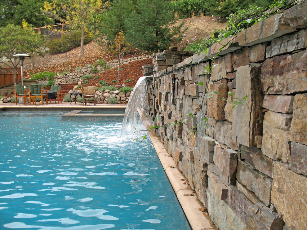 Esempio di una grande piscina monocorsia rustica rettangolare dietro casa con fontane e cemento stampato