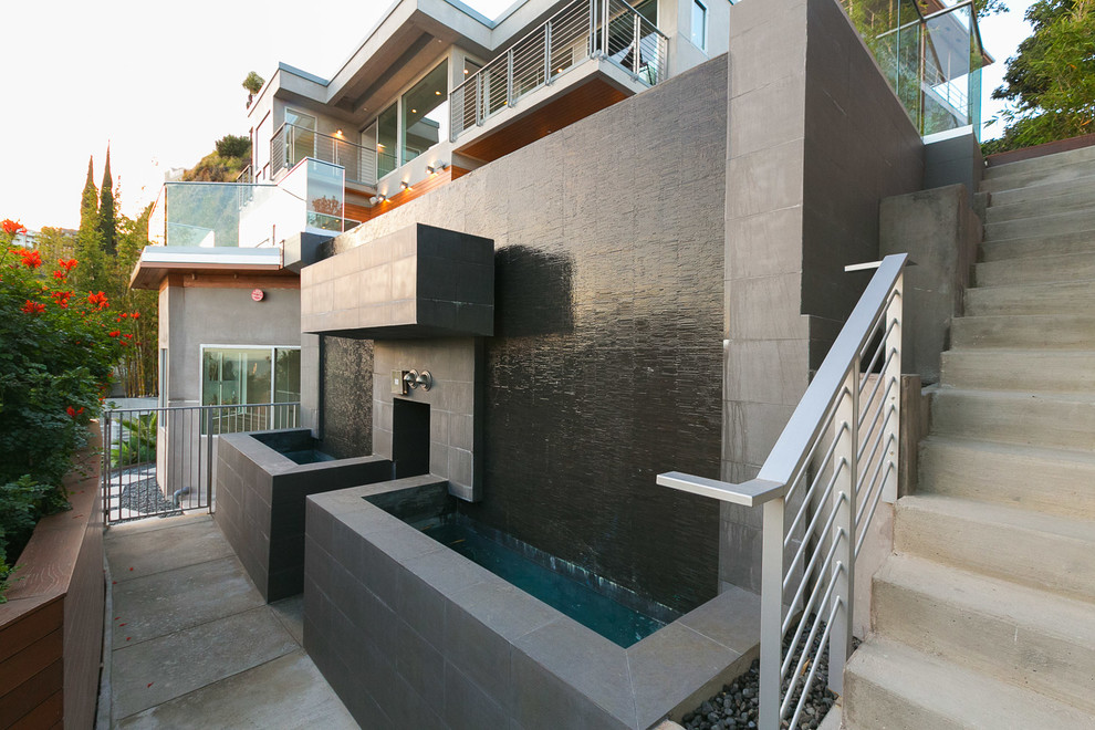 Modelo de piscina con fuente infinita minimalista grande rectangular en patio delantero con suelo de baldosas