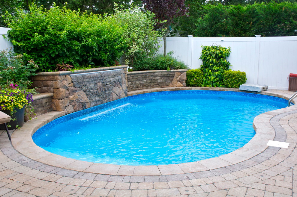 Ejemplo de piscina con fuente moderna de tamaño medio tipo riñón en patio trasero con adoquines de ladrillo