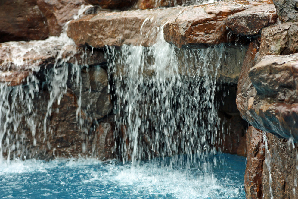Inspiration pour une grande piscine arrière traditionnelle sur mesure avec un point d'eau et des pavés en pierre naturelle.