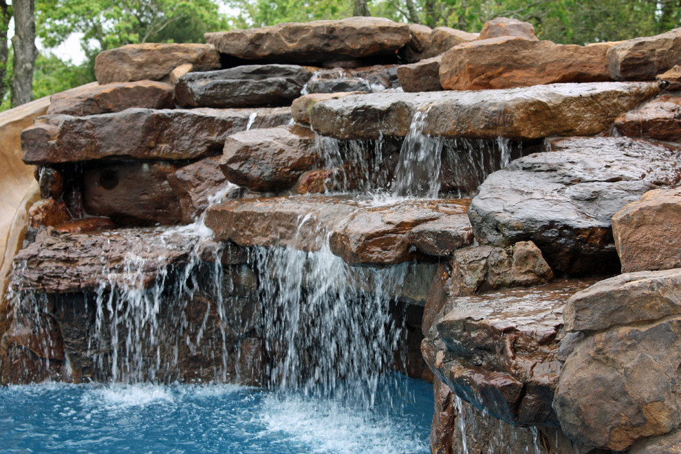 Diseño de piscina con fuente clásica grande a medida en patio trasero con adoquines de piedra natural