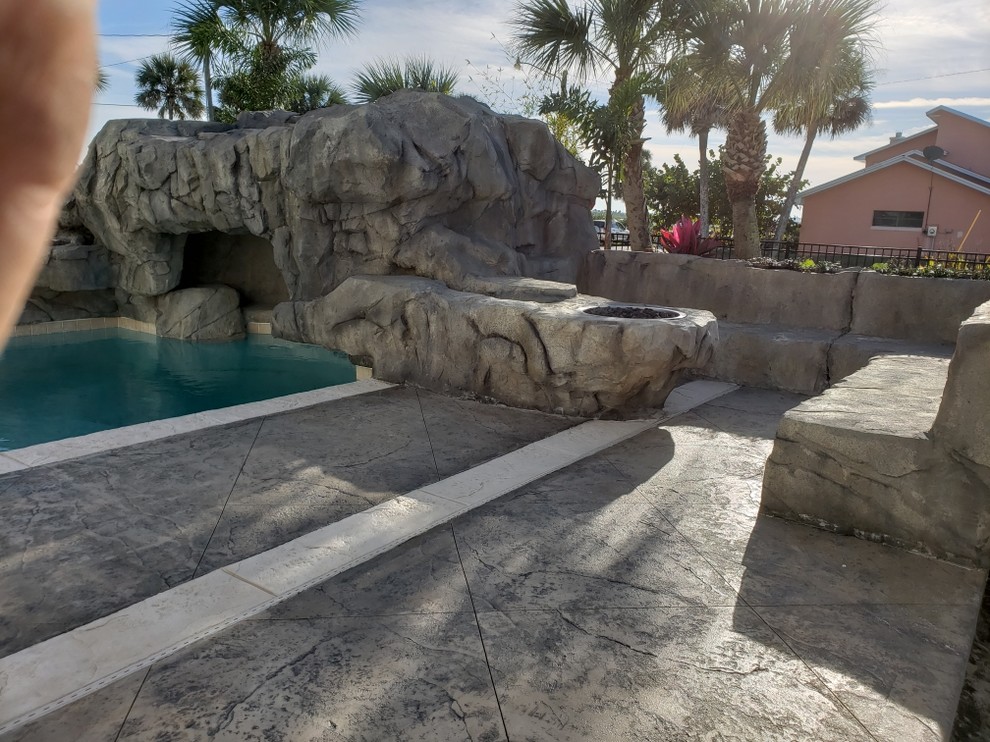 Modelo de piscina natural exótica extra grande a medida en patio trasero con suelo de hormigón estampado