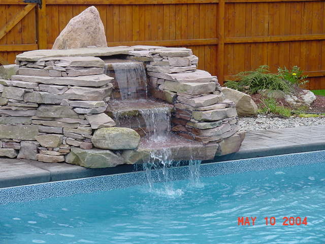 Inredning av en klassisk mellanstor pool på baksidan av huset, med en fontän
