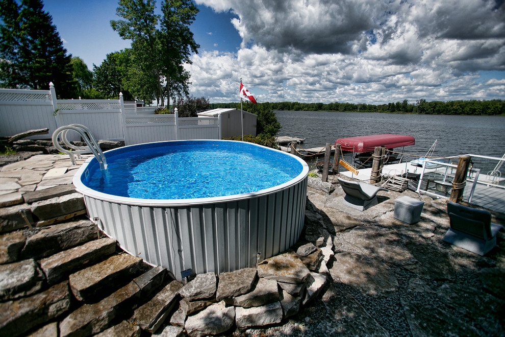 Diseño de piscina elevada rústica pequeña redondeada en patio delantero con adoquines de piedra natural