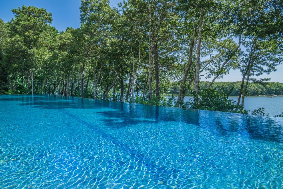 Inspiration pour une grande piscine à débordement et arrière minimaliste rectangle avec des pavés en pierre naturelle.