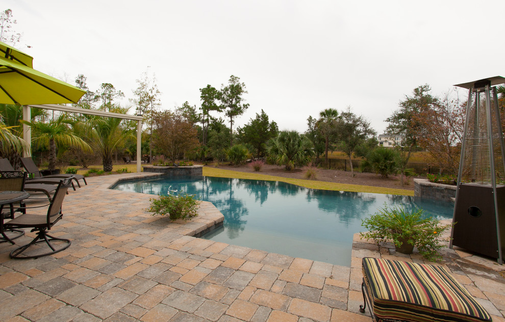 Modelo de piscina con fuente infinita tradicional grande a medida en patio trasero con adoquines de ladrillo