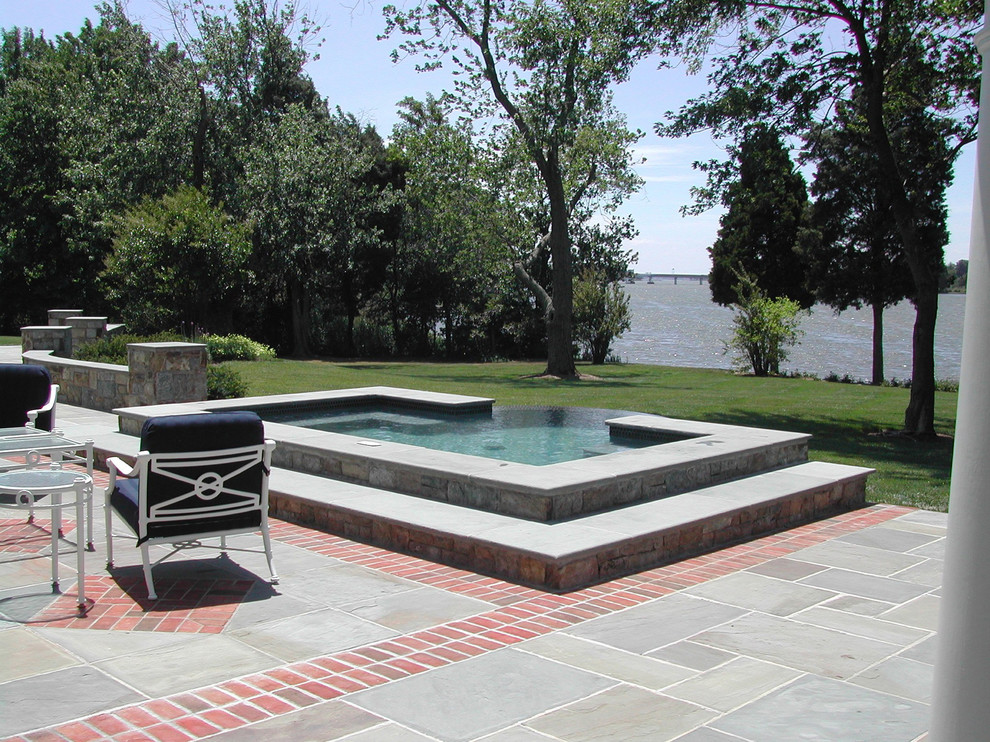 Ispirazione per un'ampia piscina tradizionale personalizzata dietro casa con pavimentazioni in pietra naturale
