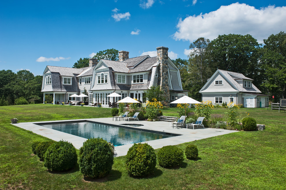 Großer Country Pool hinter dem Haus in rechteckiger Form mit Natursteinplatten in New York