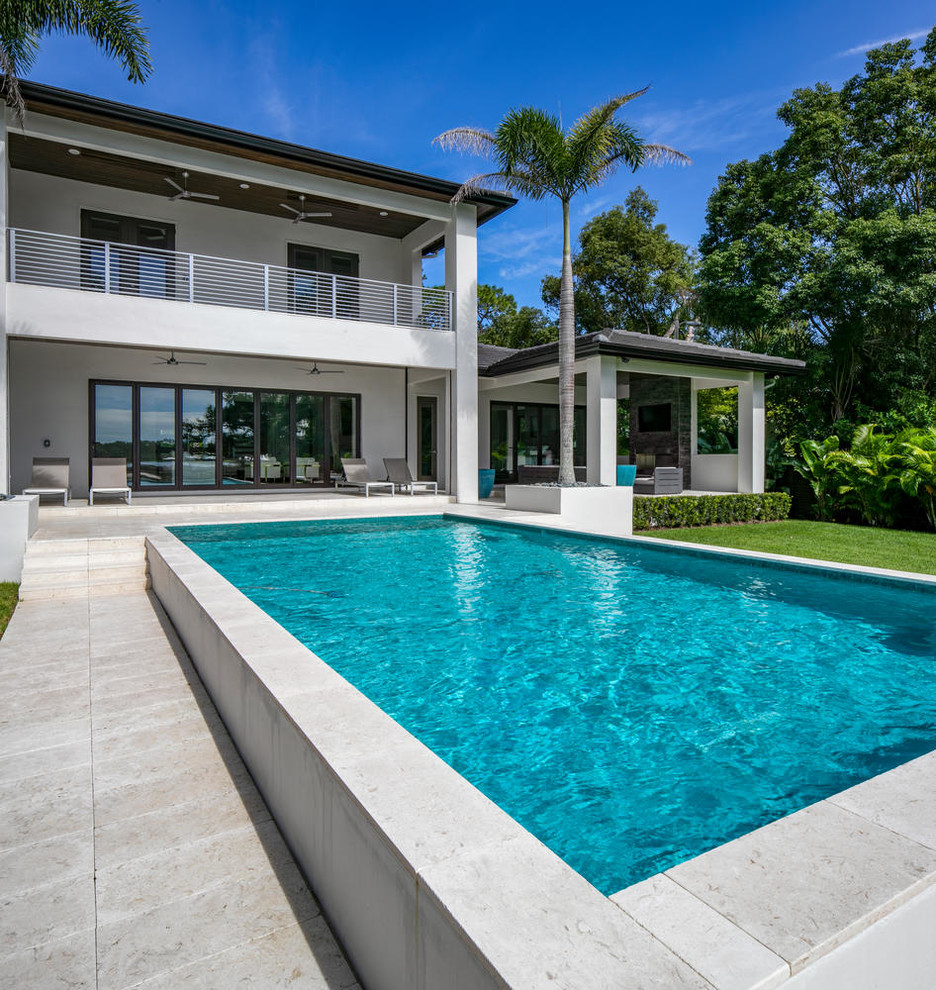 Foto de piscina minimalista rectangular en patio trasero con adoquines de piedra natural