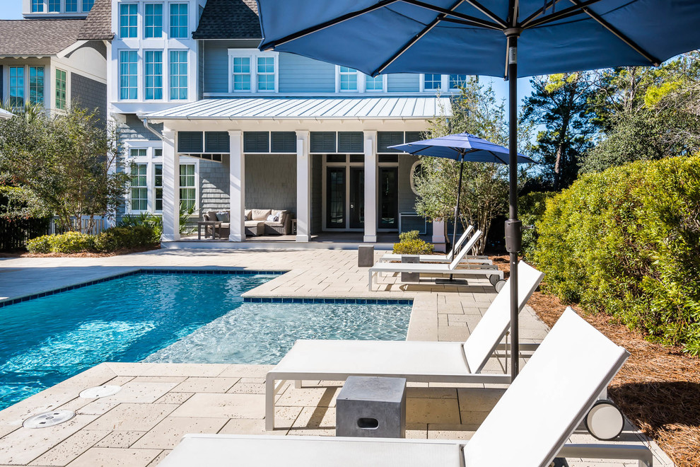 Immagine di un'ampia piscina stile marinaro personalizzata dietro casa con pavimentazioni in pietra naturale