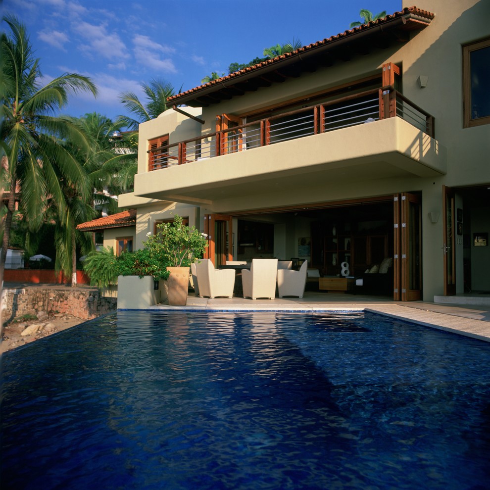 Idee per un'ampia piscina a sfioro infinito tropicale rettangolare dietro casa con pavimentazioni in pietra naturale e fontane