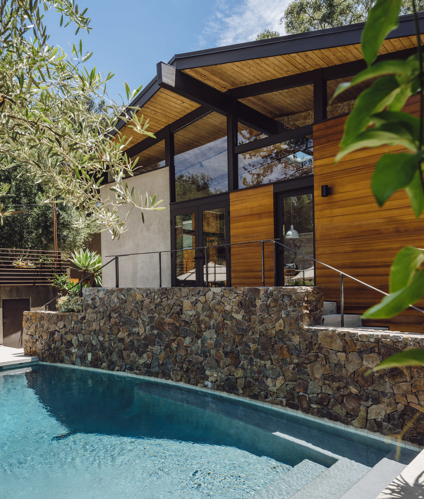 Diseño de piscina actual de tamaño medio rectangular en patio trasero con losas de hormigón