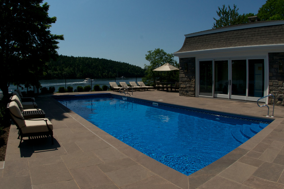 Idee per una grande piscina minimalista rettangolare dietro casa con pavimentazioni in pietra naturale