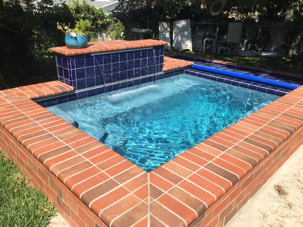 Kleiner Klassischer Pool hinter dem Haus in rechteckiger Form mit Wasserspiel und Pflastersteinen in Orange County