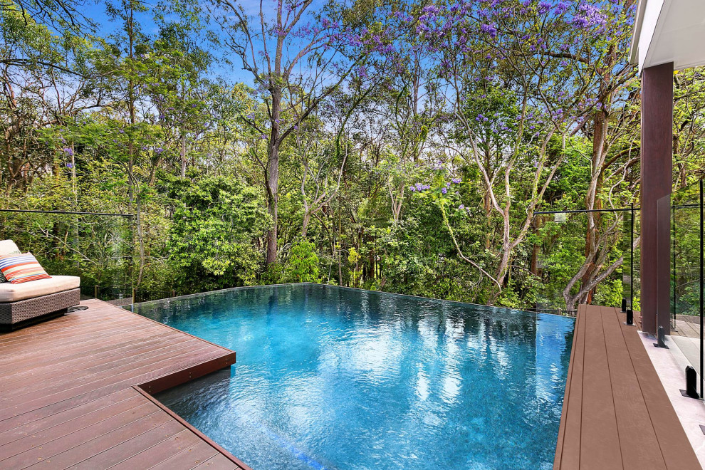 Idée de décoration pour une piscine à débordement et arrière design de taille moyenne et rectangle avec une terrasse en bois.