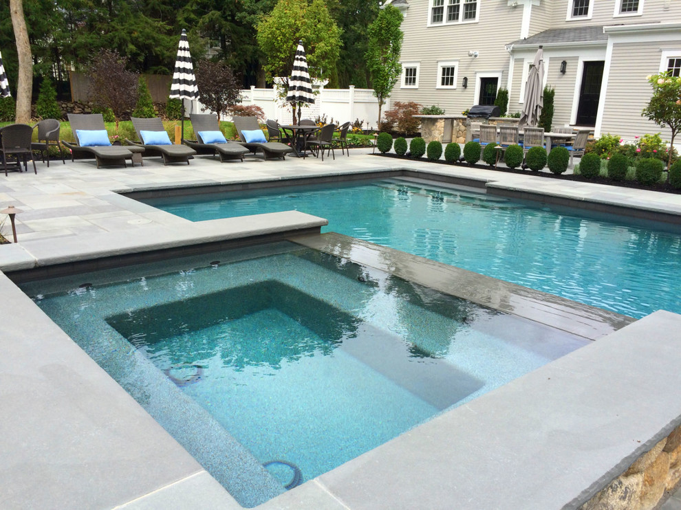 Large classic back rectangular natural swimming pool in Boston with a water feature and stamped concrete.