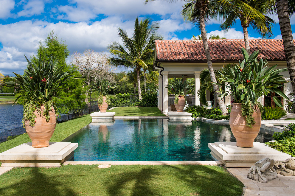 Foto di una grande piscina monocorsia tropicale rettangolare dietro casa con una vasca idromassaggio e pavimentazioni in pietra naturale
