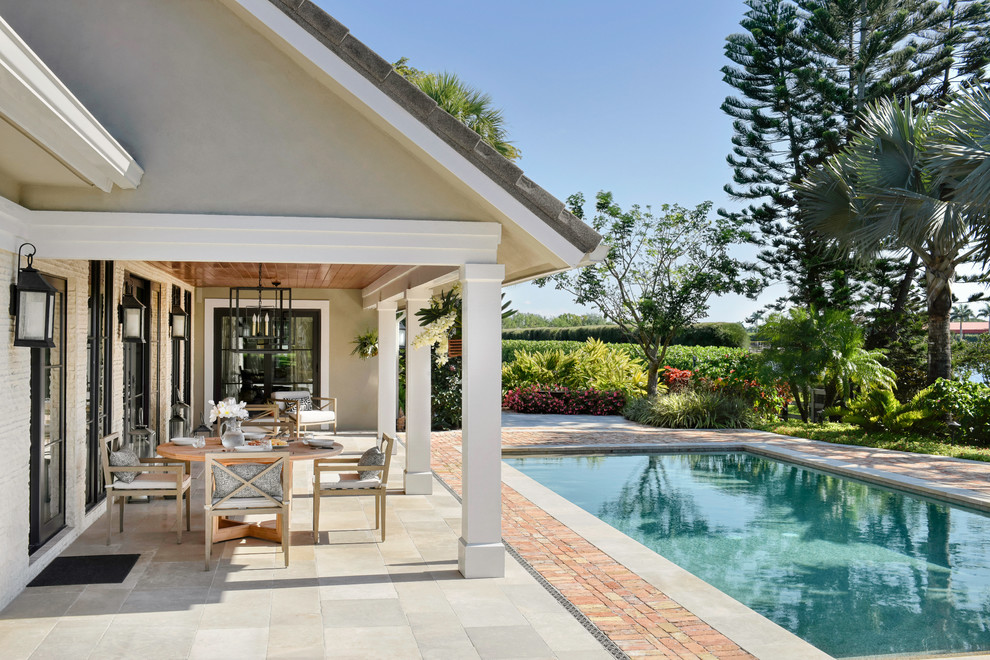Ejemplo de piscina alargada tradicional renovada de tamaño medio rectangular en patio trasero con adoquines de hormigón