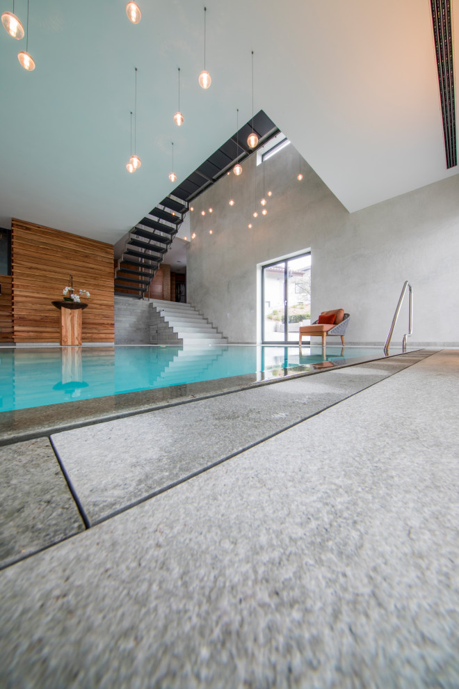 Immagine di una piscina coperta minimal personalizzata con pavimentazioni in pietra naturale