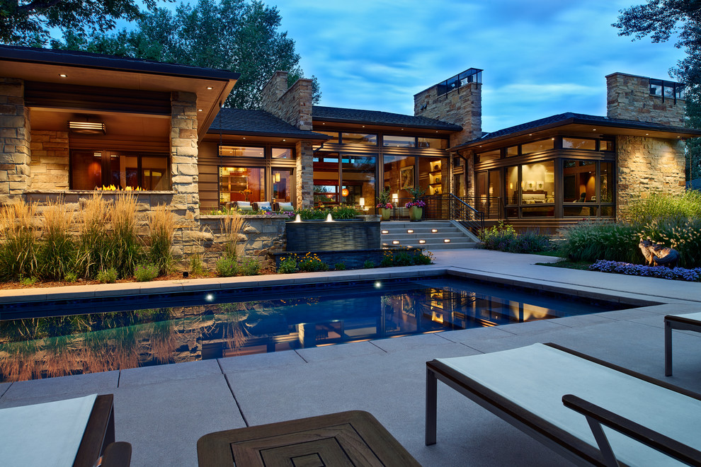 Large contemporary back rectangular lengths swimming pool in Denver with a water feature and concrete paving.