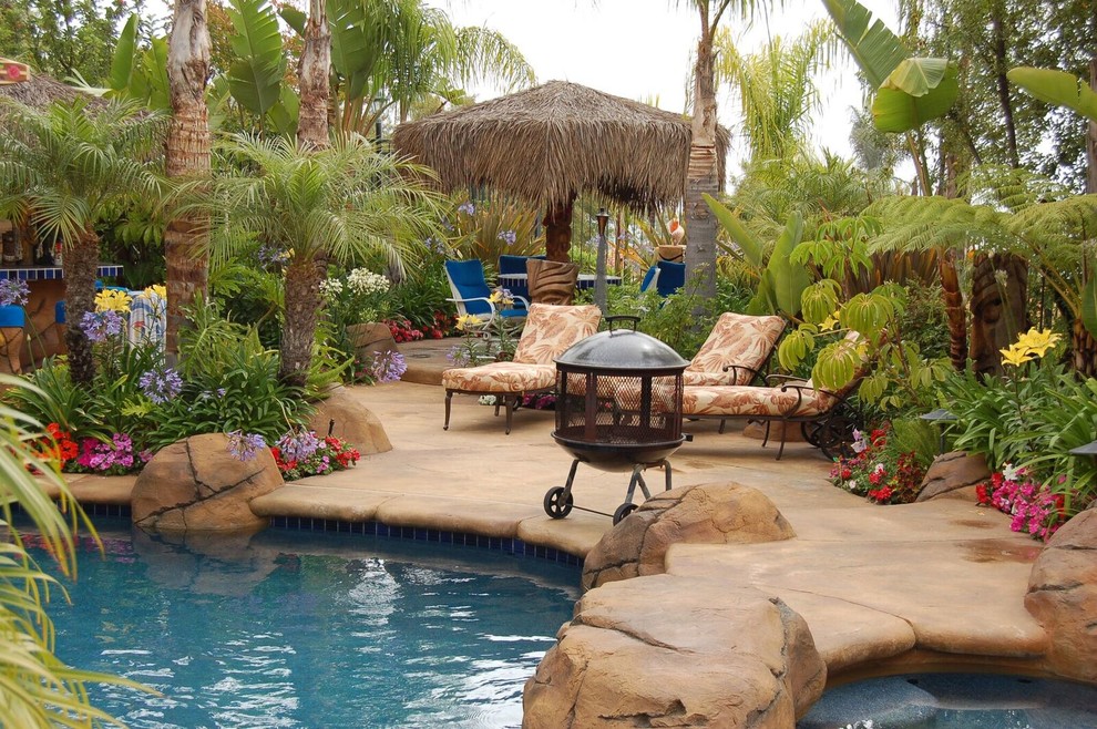 Modelo de piscinas y jacuzzis naturales tropicales de tamaño medio a medida en patio trasero con losas de hormigón