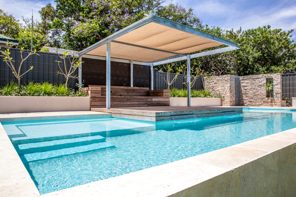 Exemple d'une grande piscine hors-sol et arrière tendance rectangle avec un point d'eau et des pavés en pierre naturelle.