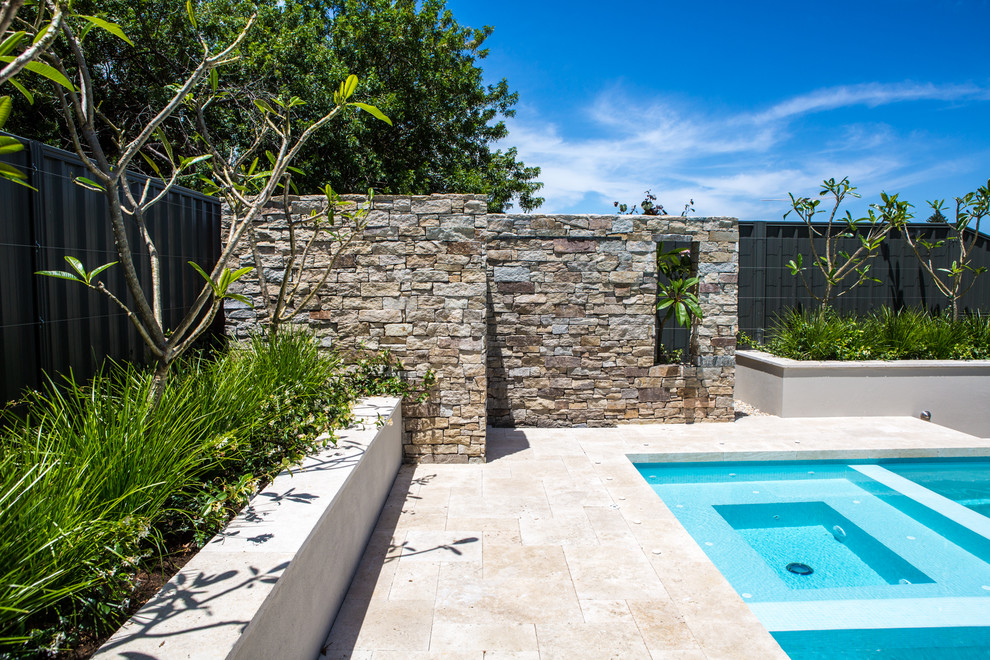 Cette image montre une grande piscine hors-sol et arrière design rectangle avec un point d'eau et des pavés en pierre naturelle.