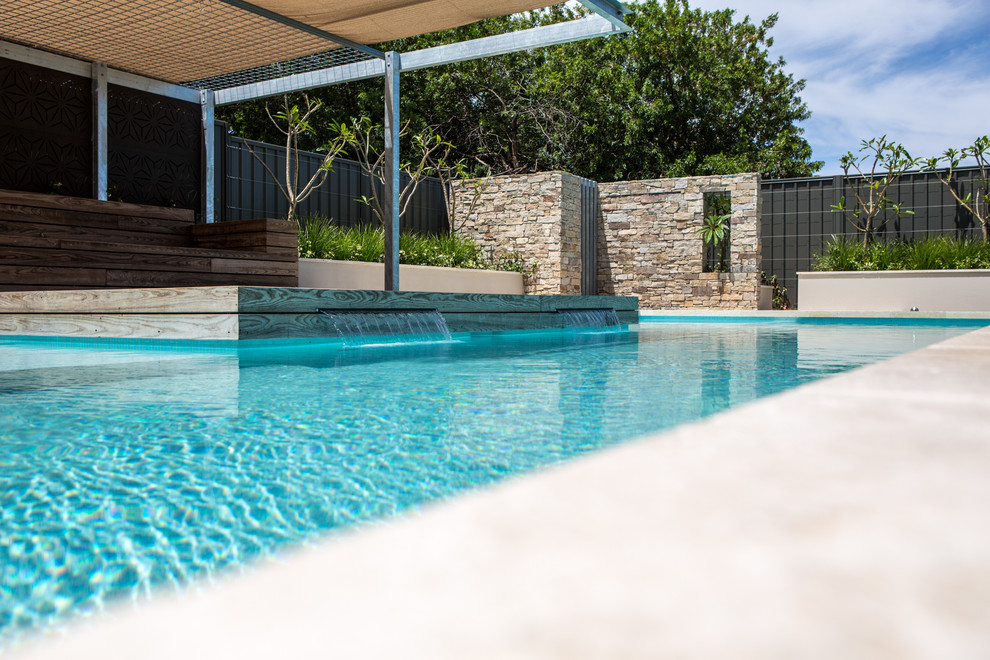 Foto di una grande piscina fuori terra contemporanea rettangolare dietro casa con fontane e pavimentazioni in pietra naturale
