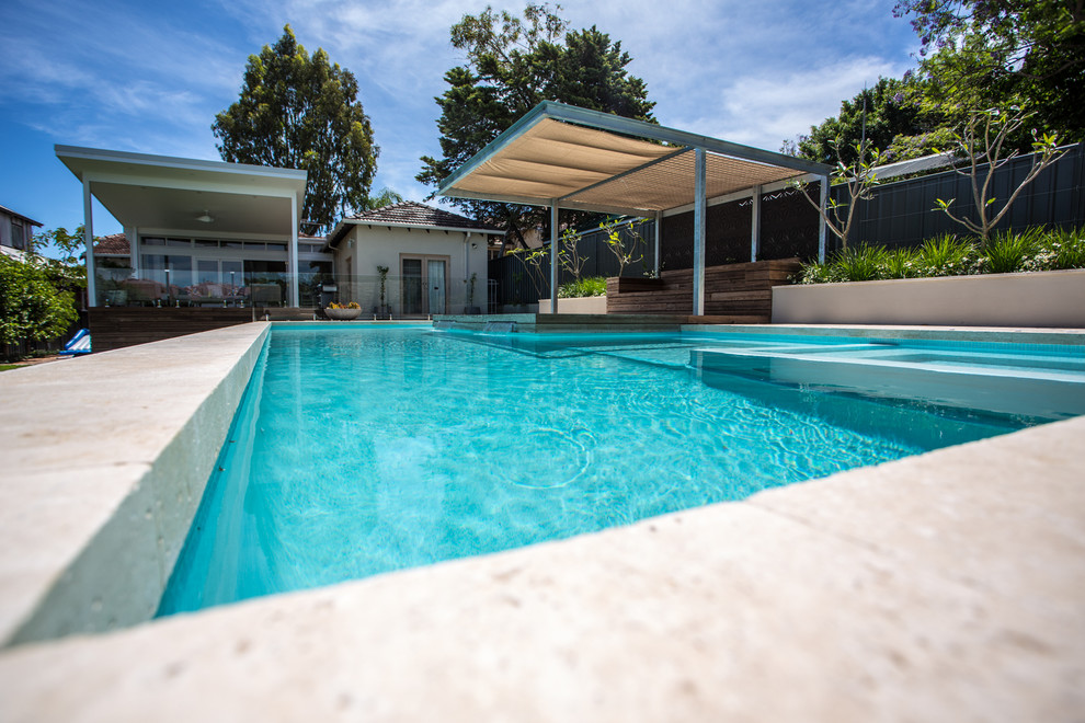 Réalisation d'une grande piscine hors-sol et arrière design rectangle avec un point d'eau et des pavés en pierre naturelle.