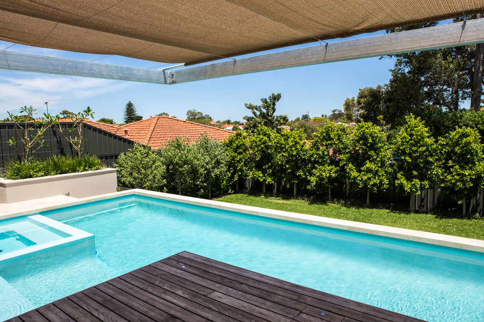 Large contemporary back rectangular above ground swimming pool in Perth with a water feature and natural stone paving.