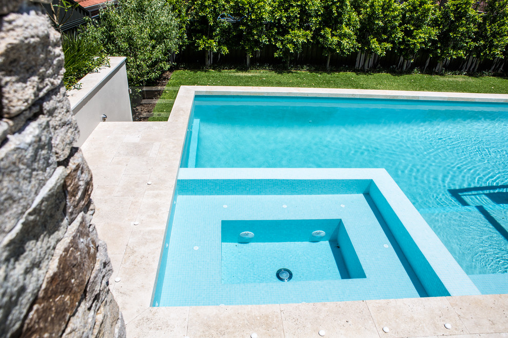 Ejemplo de piscina con fuente elevada contemporánea grande rectangular en patio trasero con adoquines de piedra natural