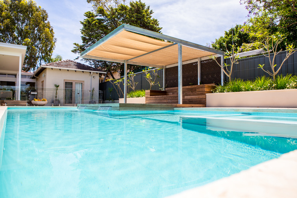 Ejemplo de piscina con fuente elevada contemporánea grande rectangular en patio trasero con adoquines de piedra natural