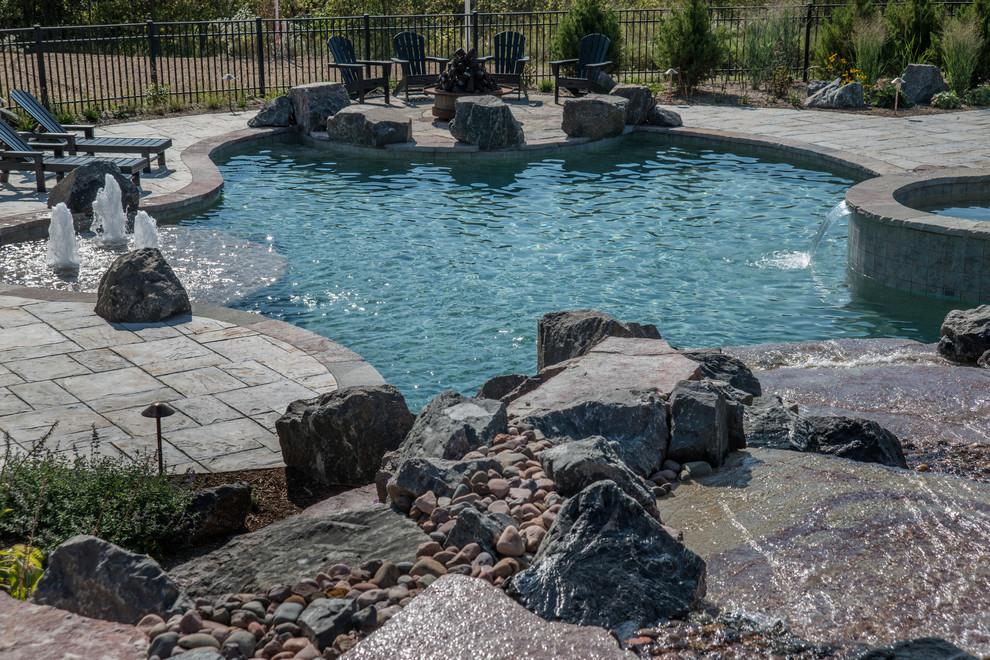 Idee per una piscina naturale rustica personalizzata di medie dimensioni e dietro casa con una vasca idromassaggio e pavimentazioni in cemento