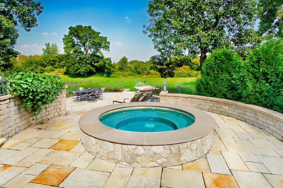 Cette image montre une petite piscine hors-sol et arrière traditionnelle ronde avec un bain bouillonnant et des pavés en pierre naturelle.