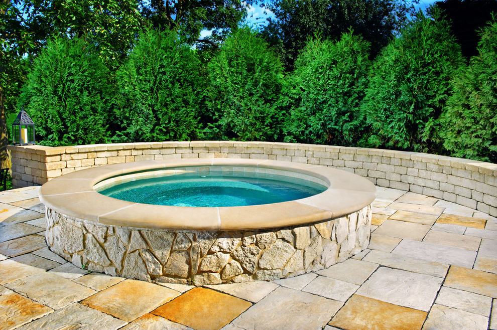 Ispirazione per una piccola piscina fuori terra tradizionale rotonda dietro casa con una vasca idromassaggio e pavimentazioni in pietra naturale