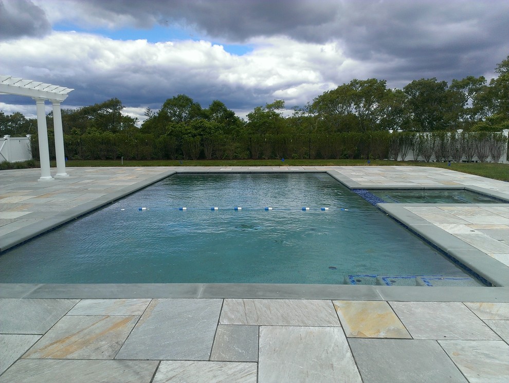 На фото: огромный естественный, прямоугольный бассейн на заднем дворе в стиле модернизм с джакузи и покрытием из каменной брусчатки